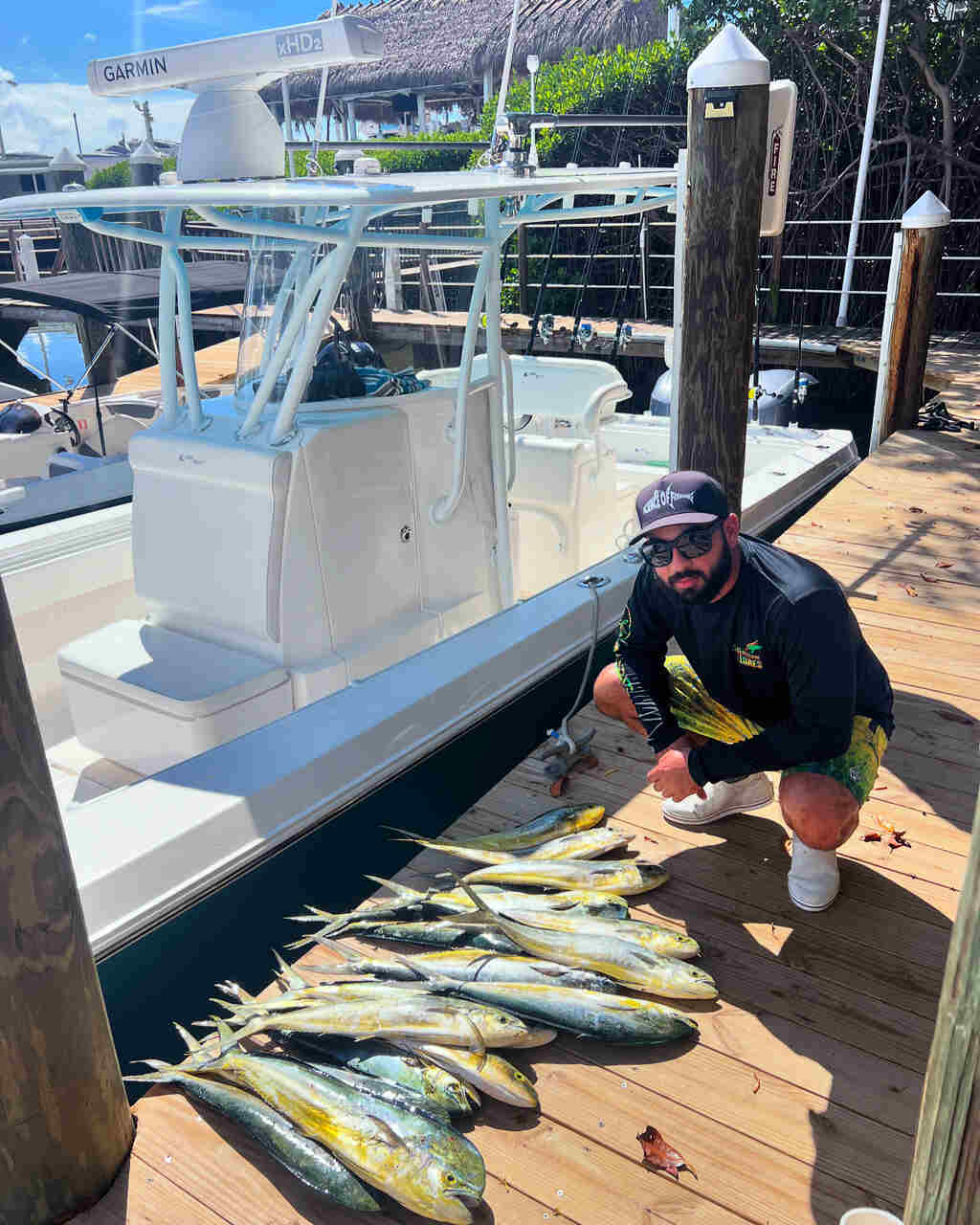 A fisherman kneeling next to a row of fish in Coconut Grove