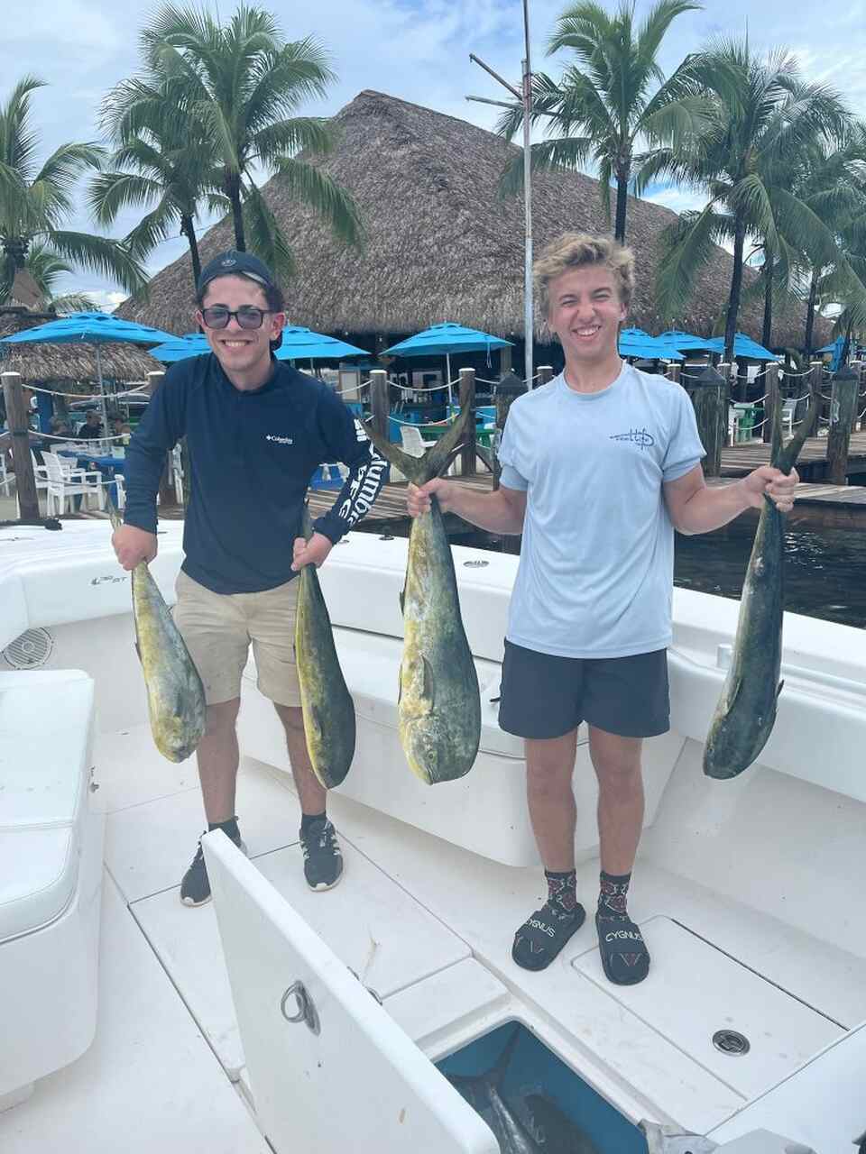 Two people holding fish on a boat in Coral Gables