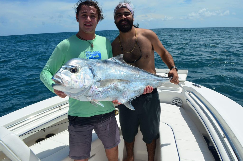 Two men with a large fish on a charter boat in North Miami