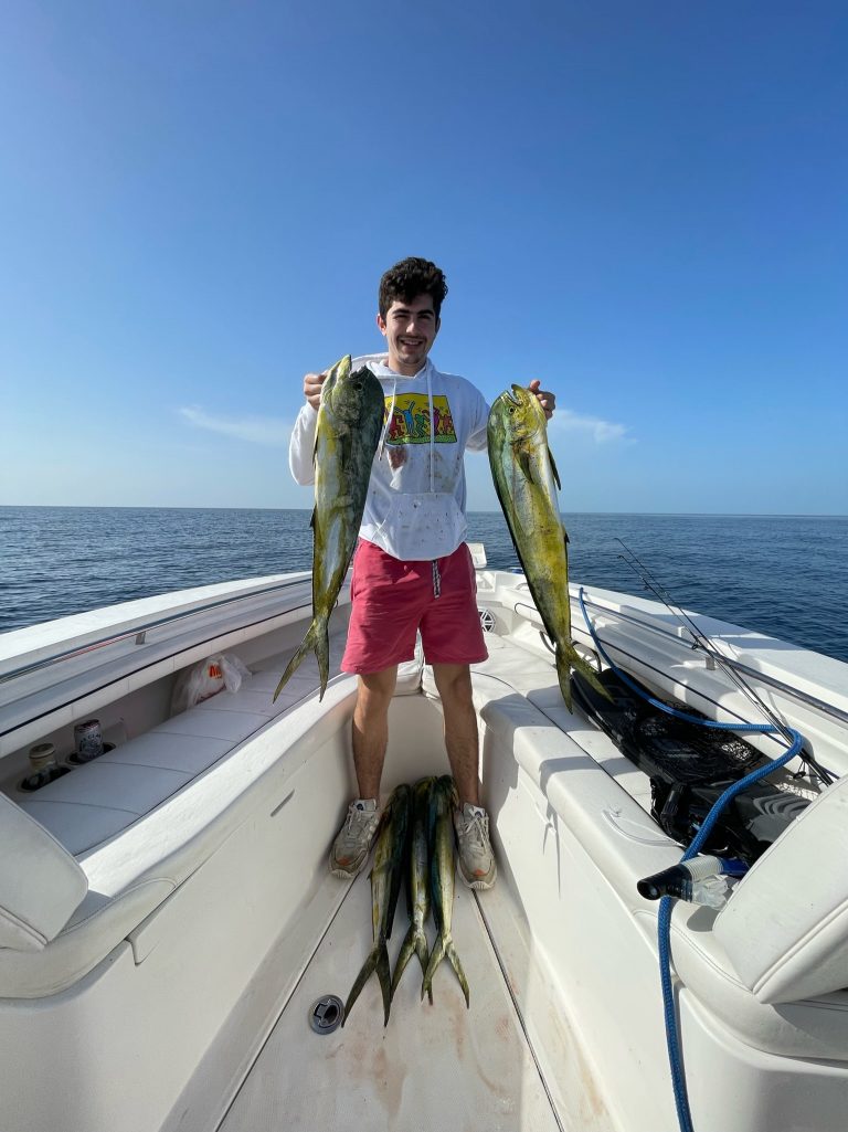 A fisherman holding two fish on a boat in Coconut Grove