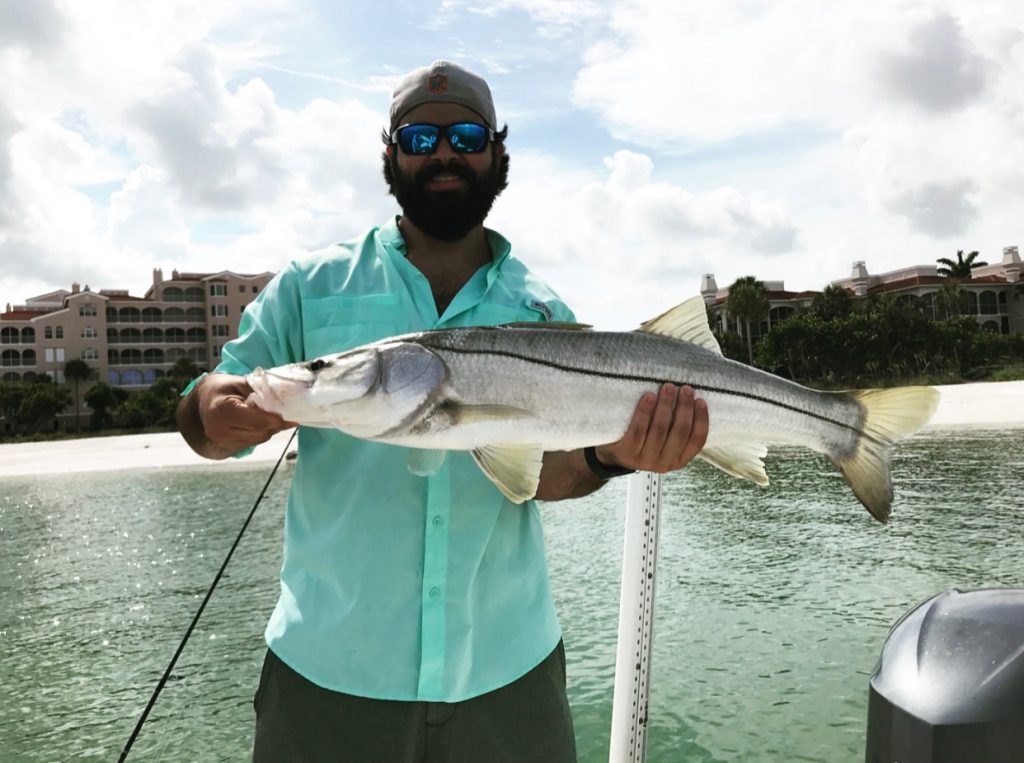 A fisherman showing off a fish caught during a Miami fishing charter