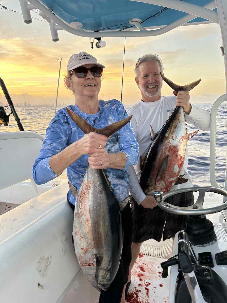 Two people holding fish on a boat during a Coral Gables trip