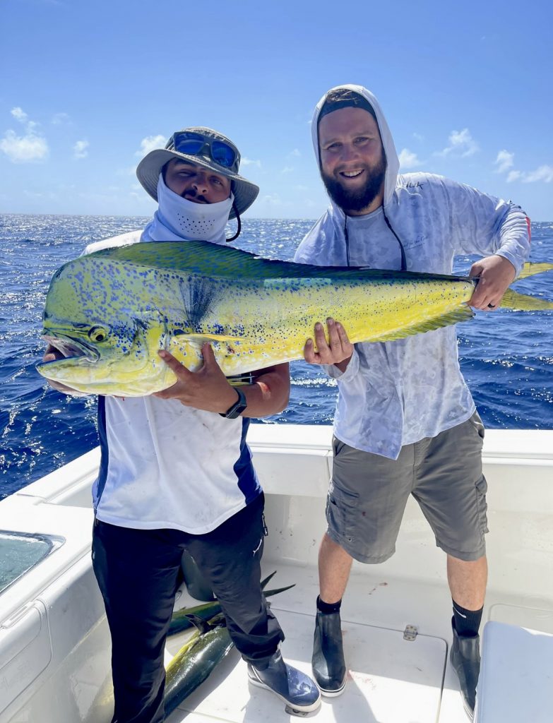 Two men with a large fish on a boat in Coral Gables