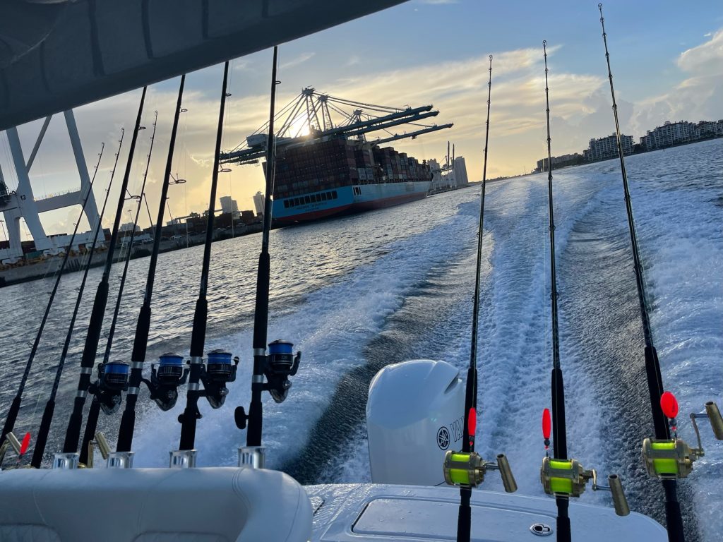 A boat with fishing poles and a large ship in the background in Miami