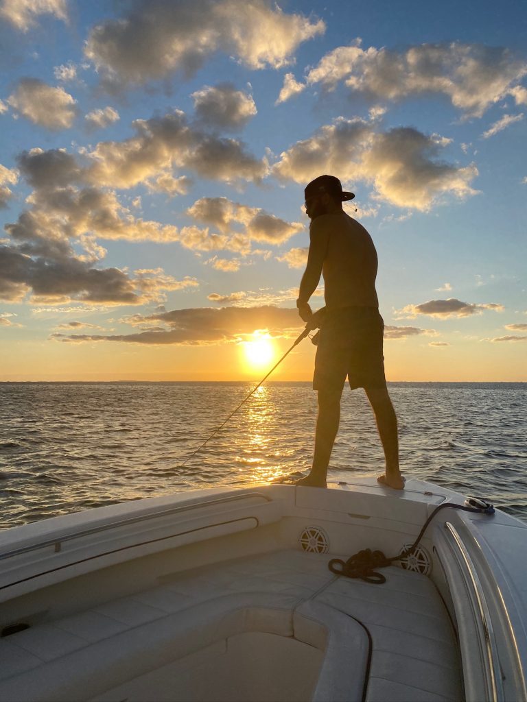 A person standing on a boat with a fishing pole in North Miami
