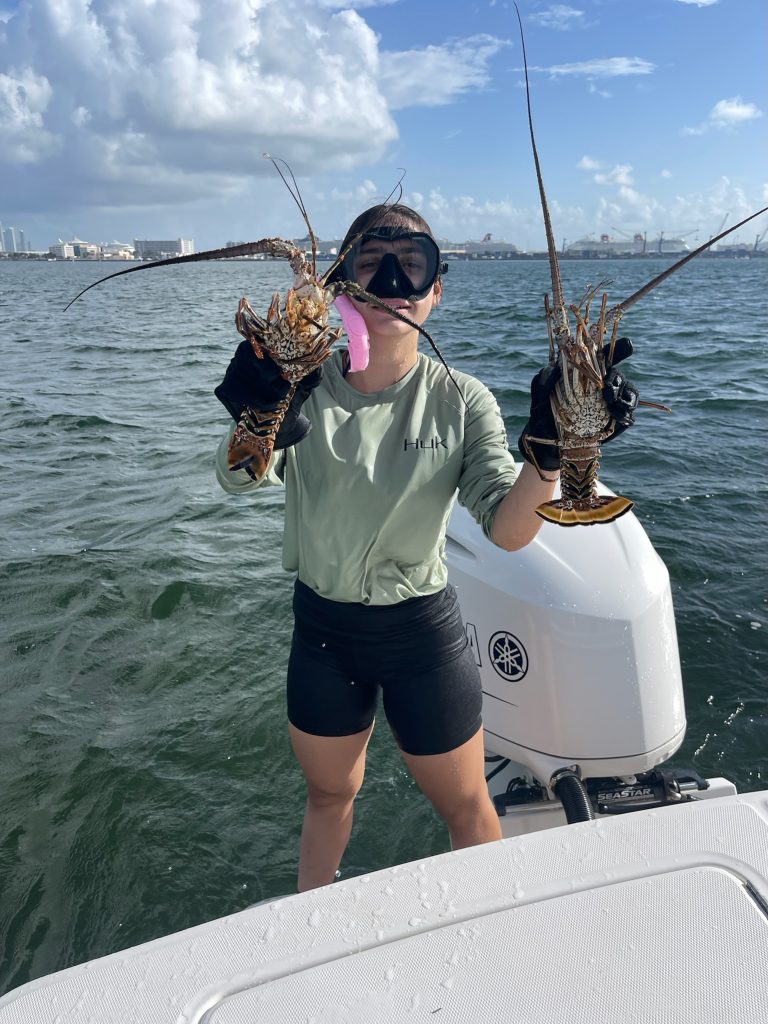 A fisherman holding lobsters in the water in Coconut Grove