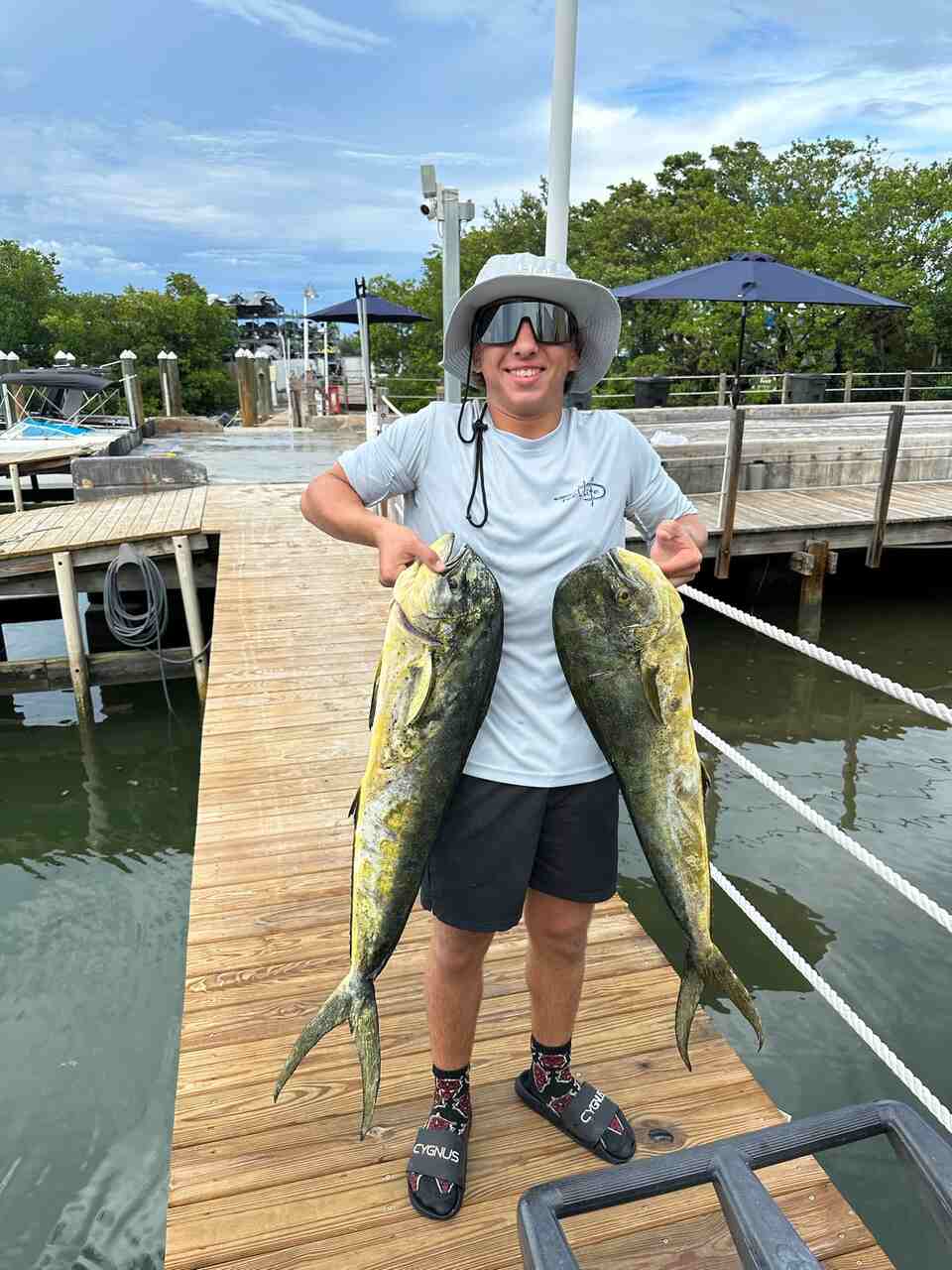 A person holding two fish on a dock in Brickell